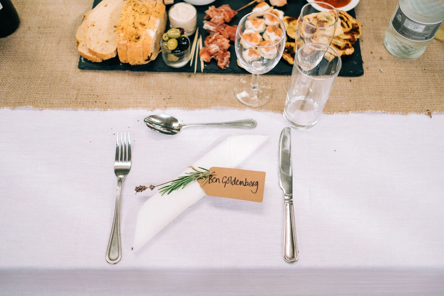 Close-up of appetizer plates and place settings on white tablecloth at wedding reception.