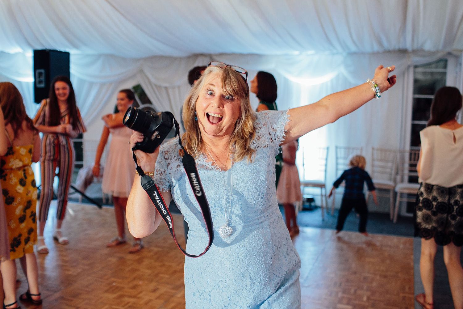 Wedding party dancing and celebrating joyfully in an indoor venue.
