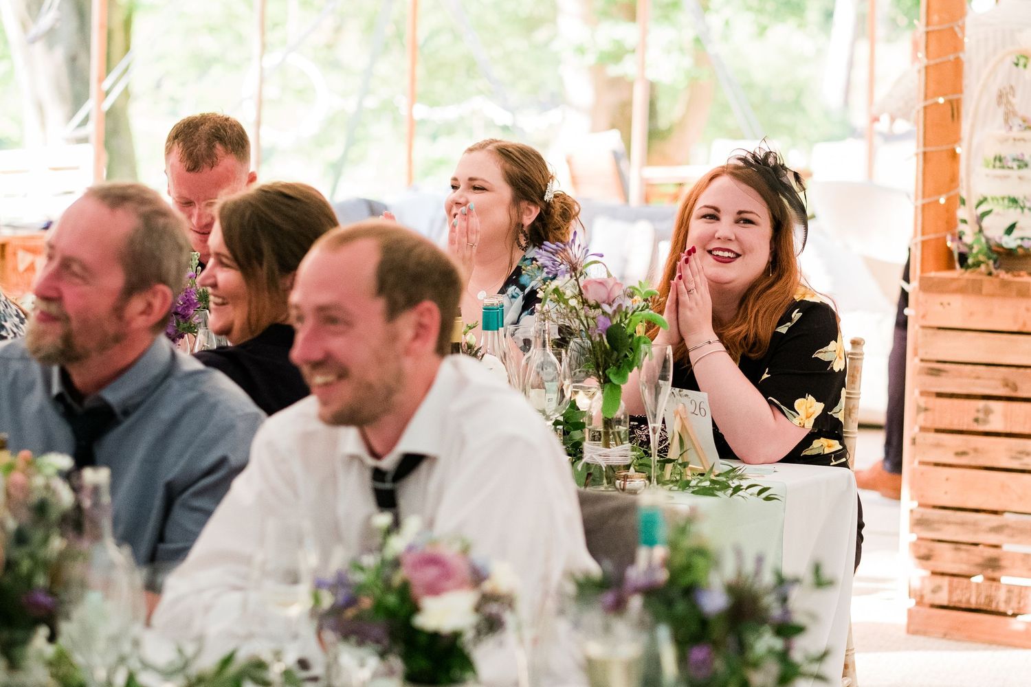 Guests sharing laughs during wedding reception speeches at decorated banquet tables.