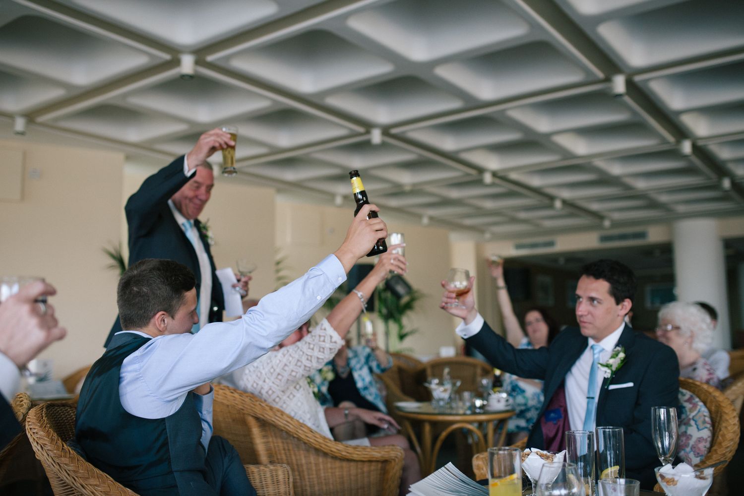 Wedding reception guests dancing and celebrating under a modern ceiling with geometric patterns.