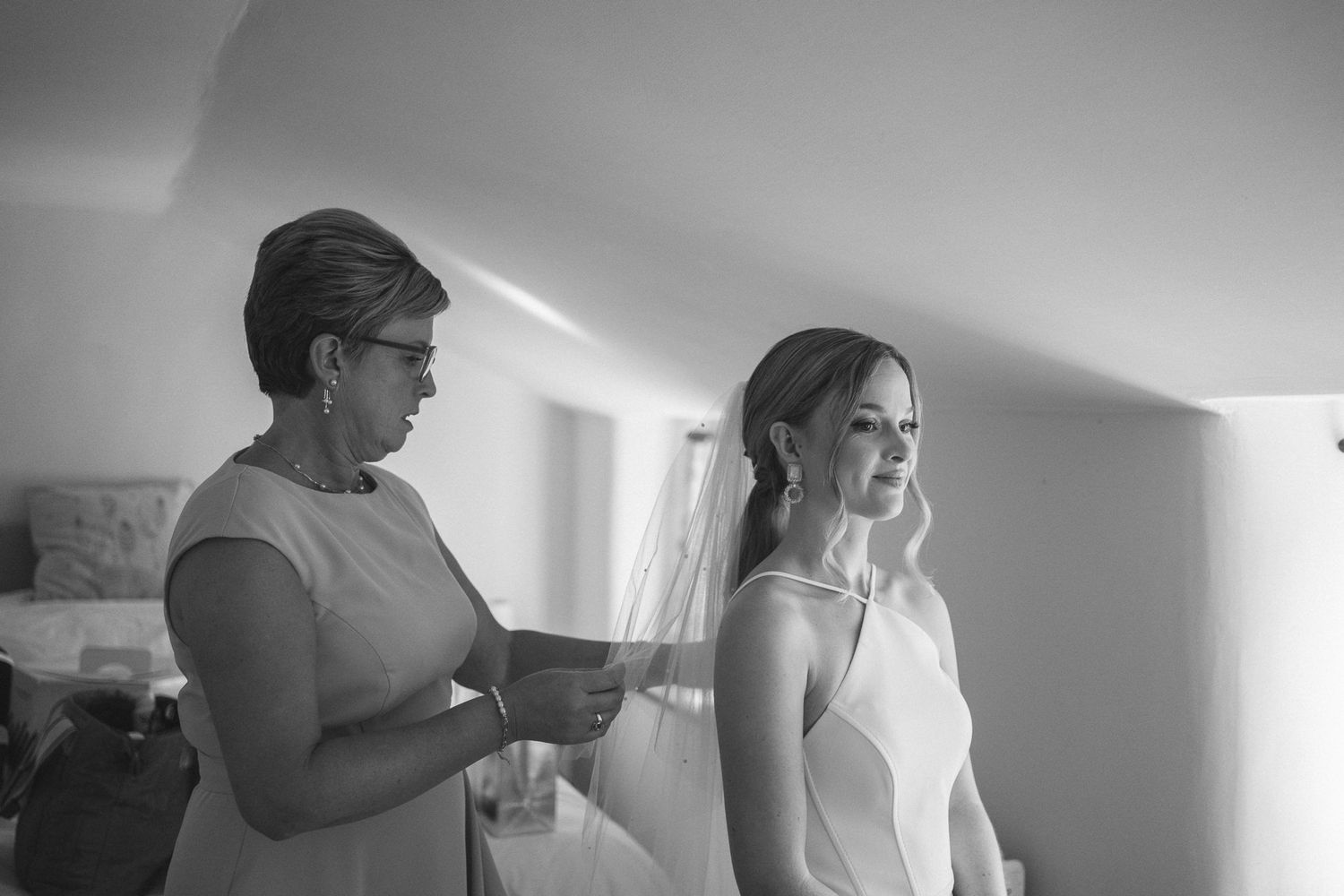 A black and white image showing final touches being made to bridal preparation.