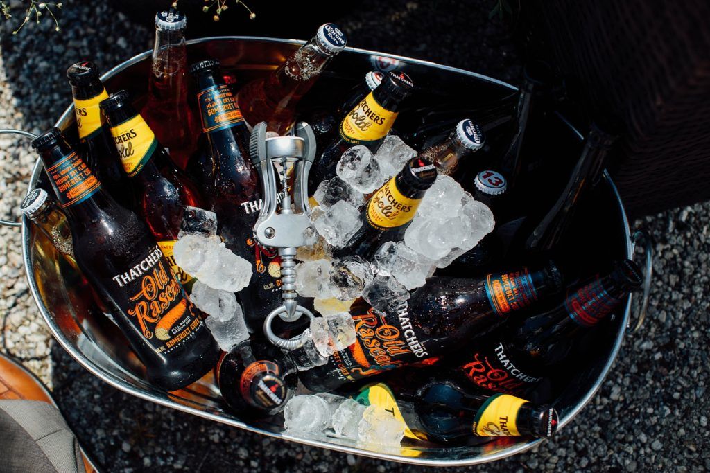 Ice bucket filled with assorted beer and beverage bottles at an outdoor event.