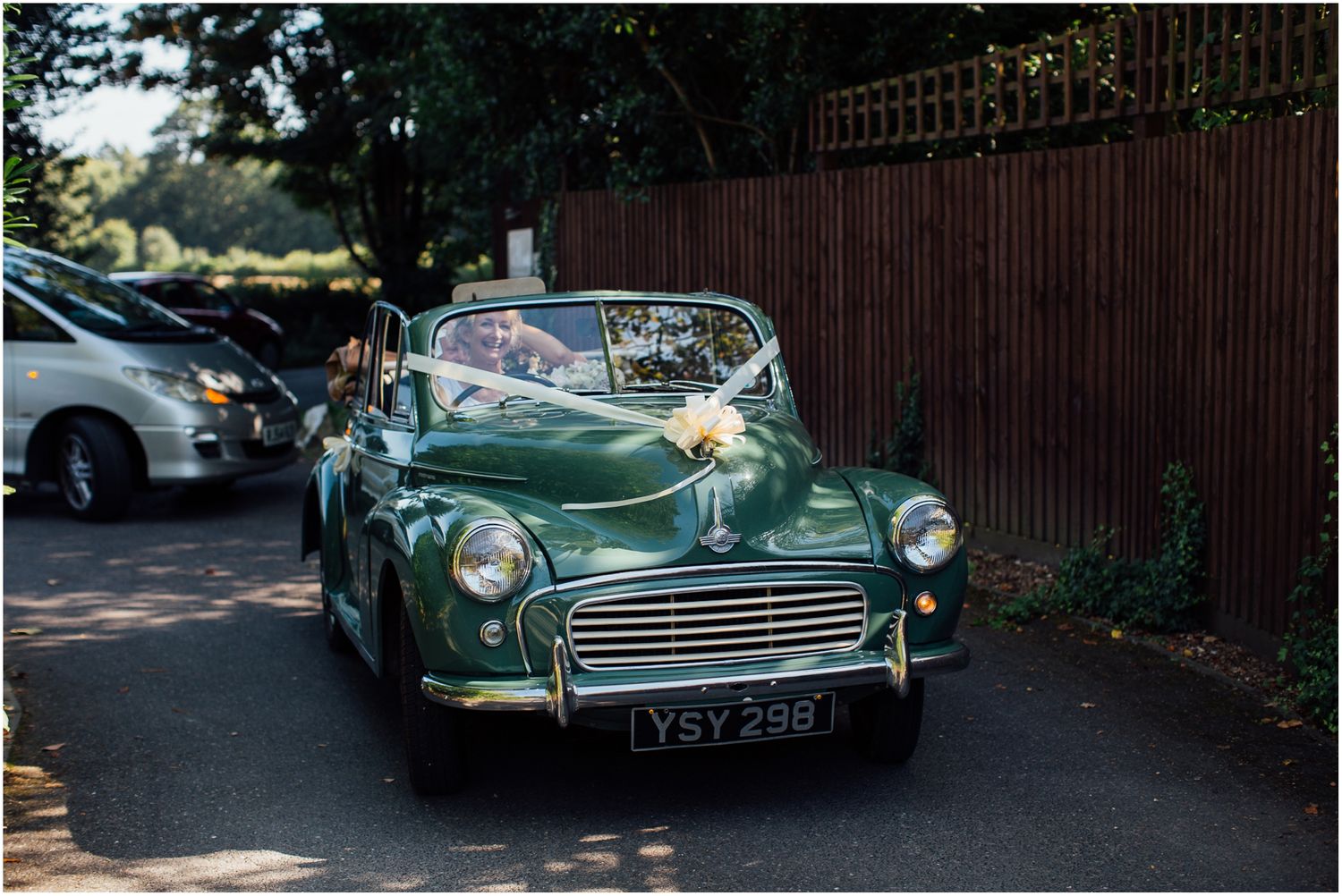 A classic green Morris Minor vintage car parked on a residential street.