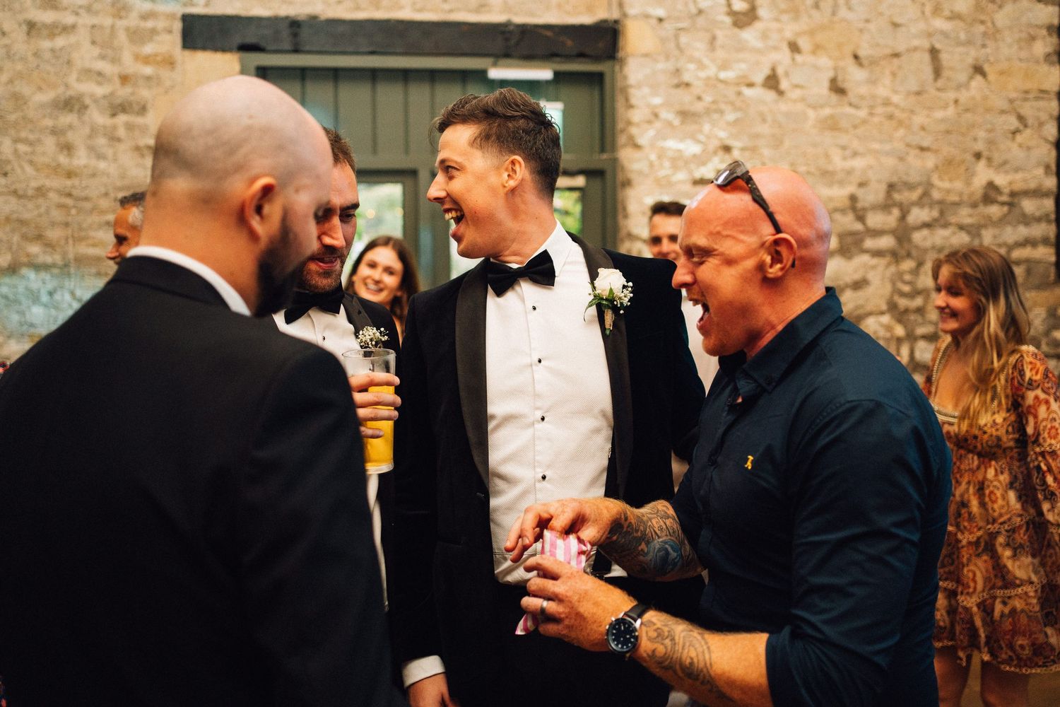 Wedding guests mingling and socializing in an elegant rustic venue with stone walls.