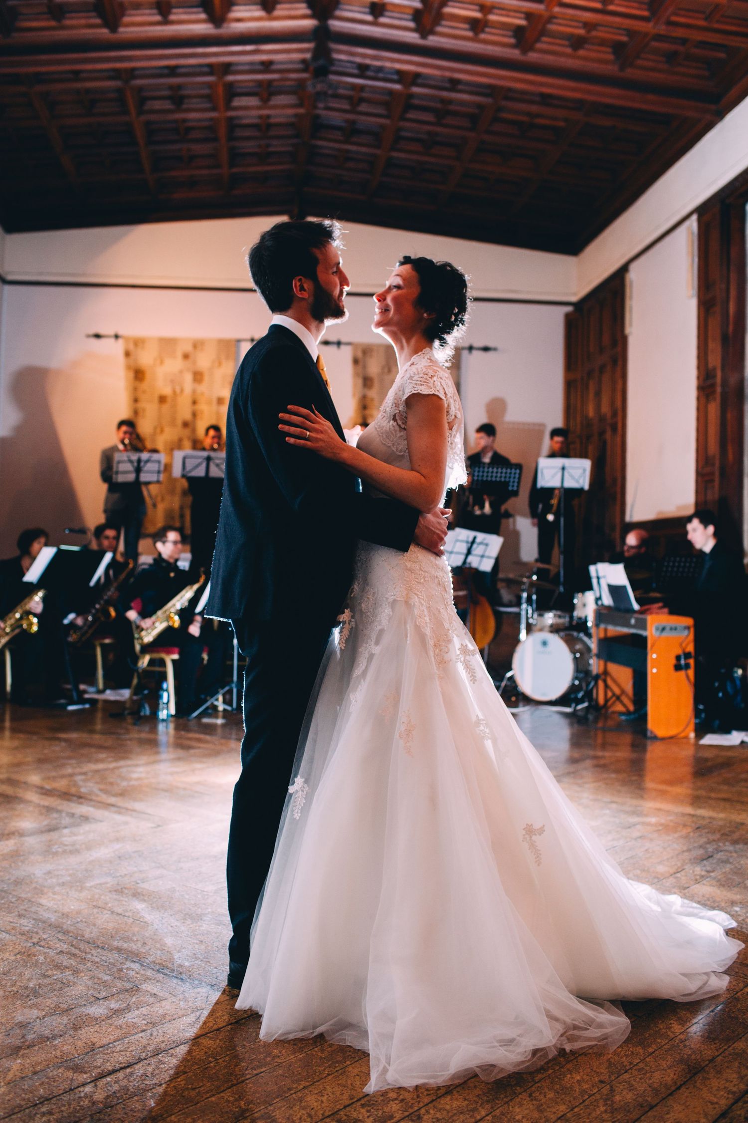 A romantic dance moment captured in a reception hall with a live band performing.
