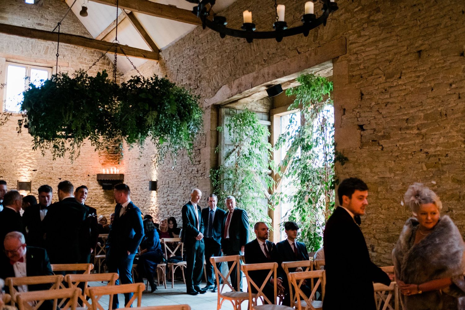 Wedding guests mingling in a converted stone barn with ambient lighting.
