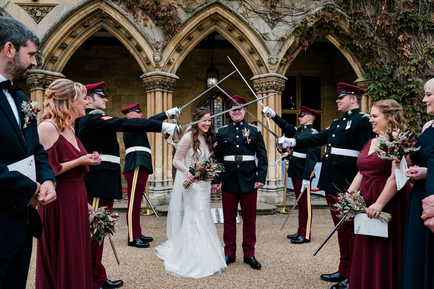 Wedding ceremony taking place under gothic stone arches with guests watching.