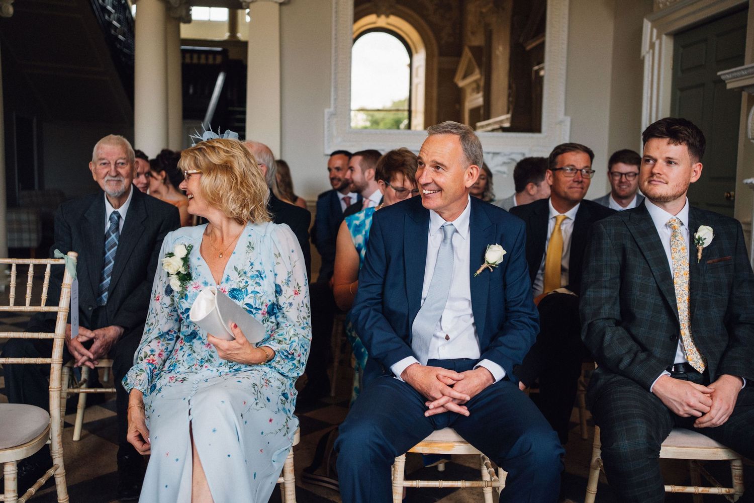 Wedding guests in formal attire socialize and mingle during an indoor reception event.