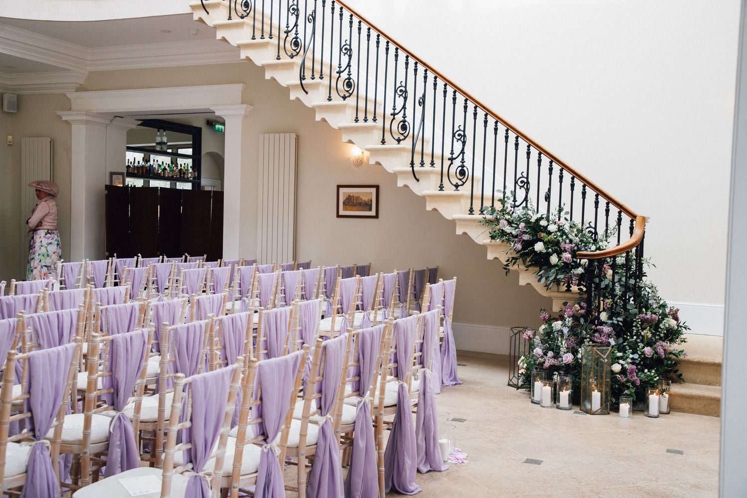 Elegant staircase decorated with white floral arrangements and purple chair covers for a wedding ceremony.