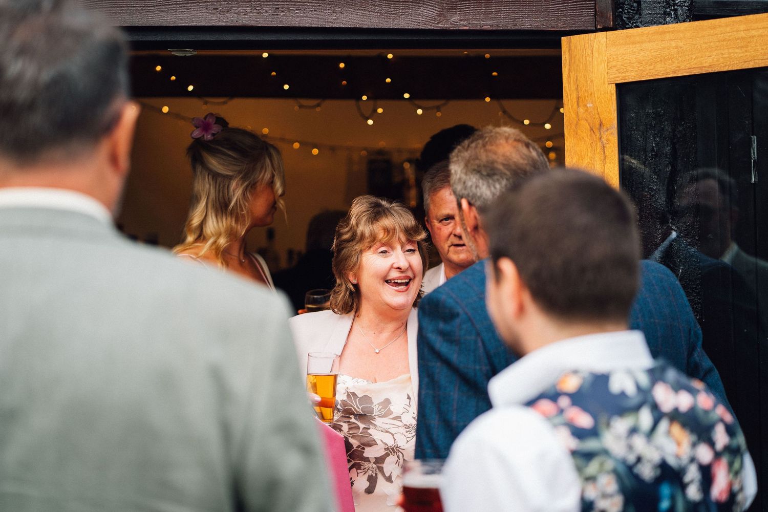People gather and socialize at a bar or restaurant with drinks in a warm, dimly lit atmosphere.