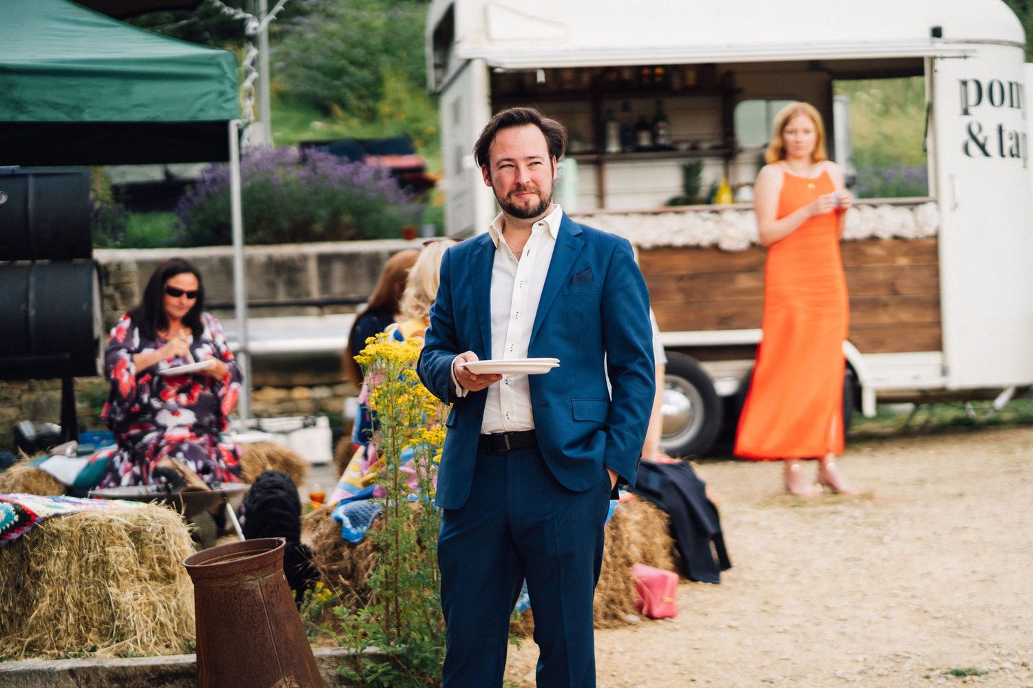 Wedding guests gathered outside a rustic barn venue during a summer celebration.