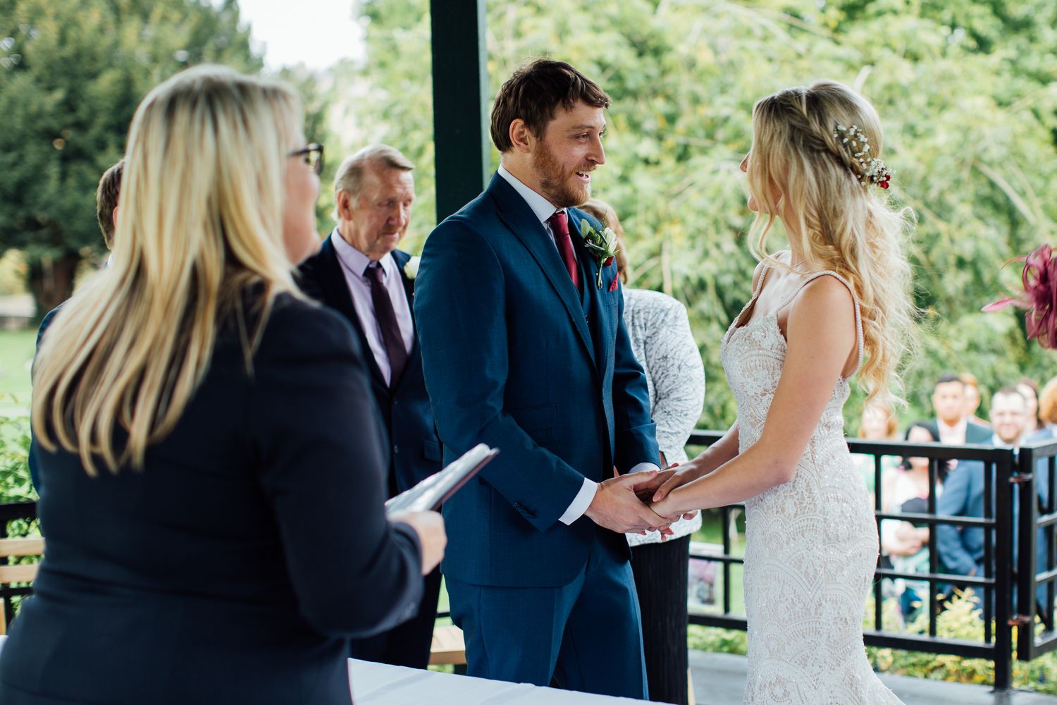 Wedding guests gather outdoors in a garden setting for a celebration in natural light.