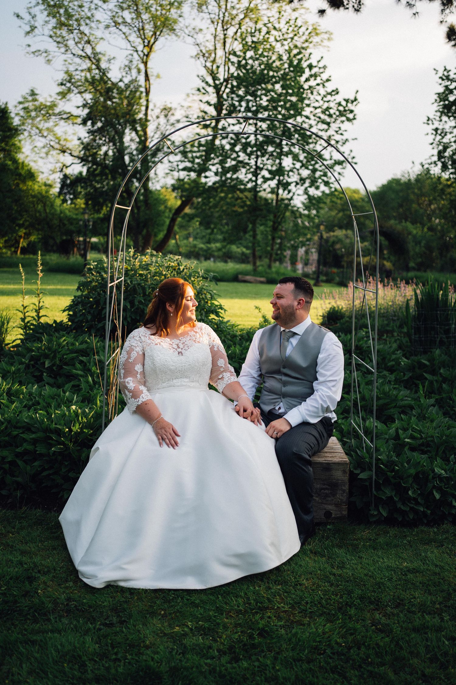 Couple sitting together on outdoor swings during sunset in a garden setting.