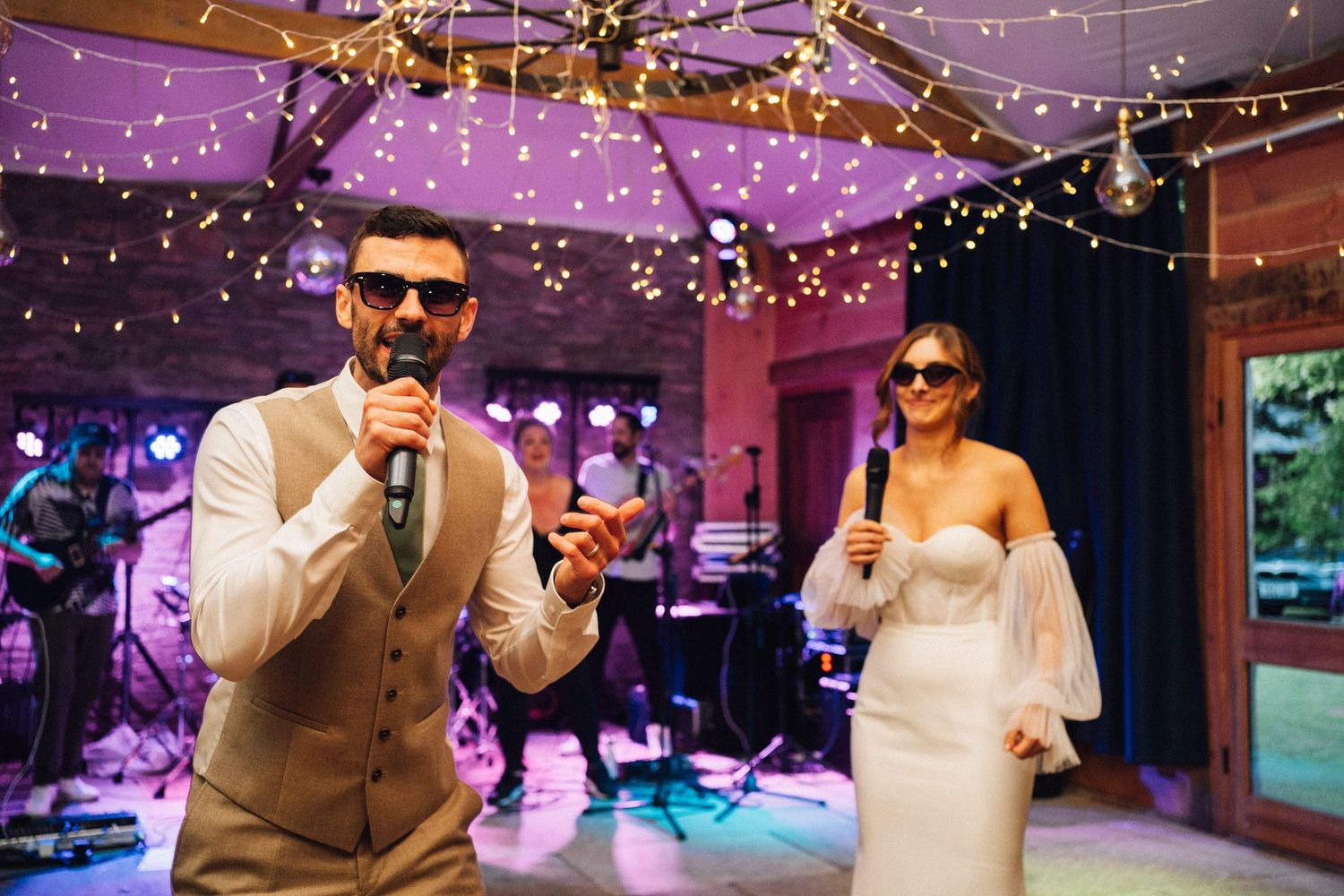Wedding reception dance floor illuminated with string lights and purple lighting creating a romantic atmosphere.