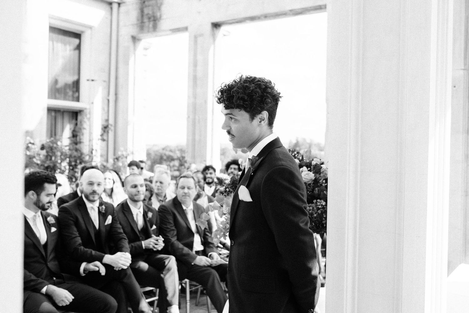 A black and white photograph of a wedding ceremony with guests seated in rows.