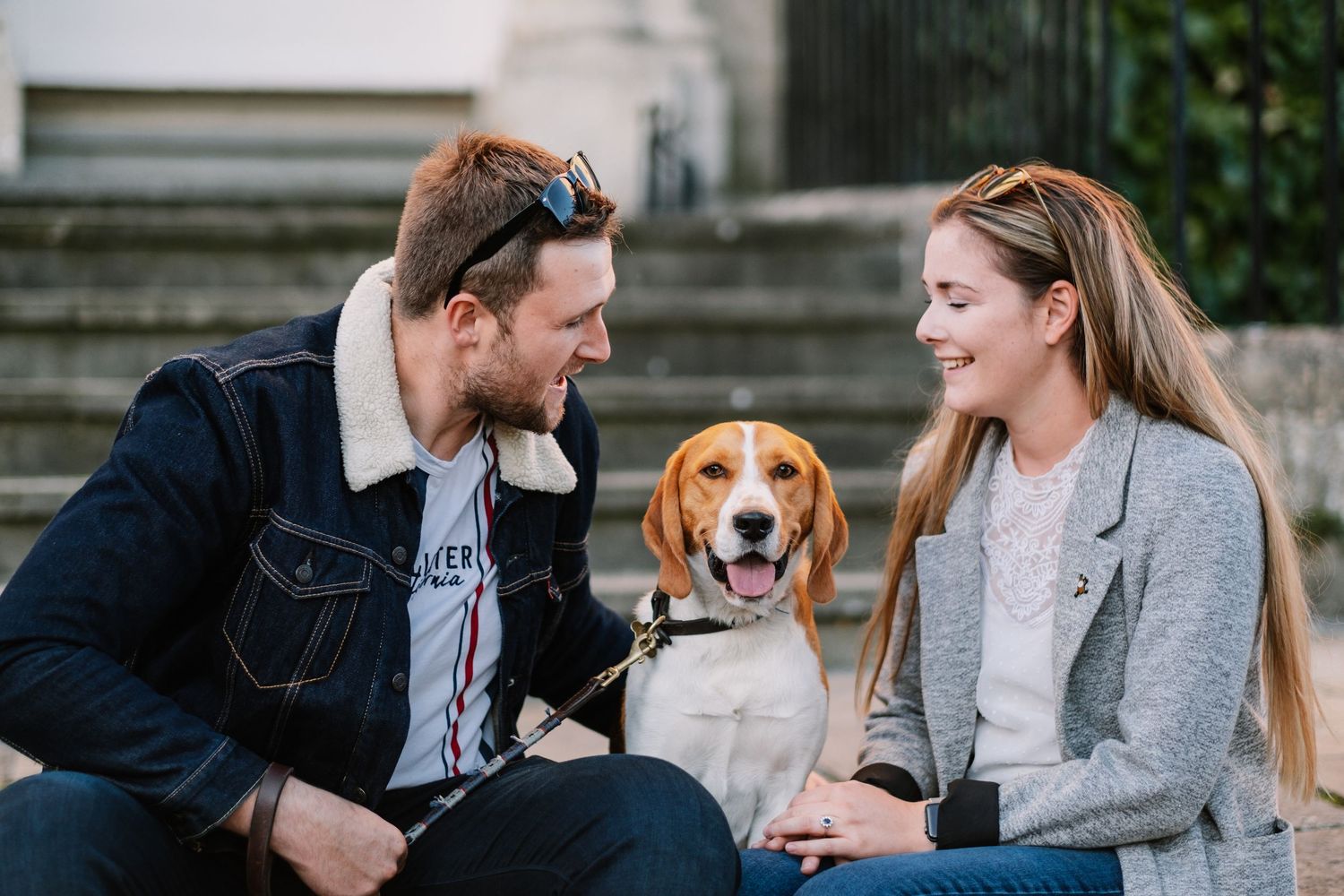 A couple walks their golden retriever dog along a scenic path during an engagement photoshoot.