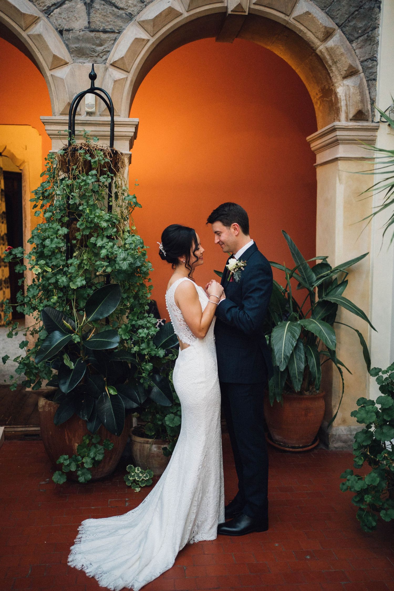 Romantic wedding portraits captured under Spanish-style arches with terracotta floors and lush greenery.