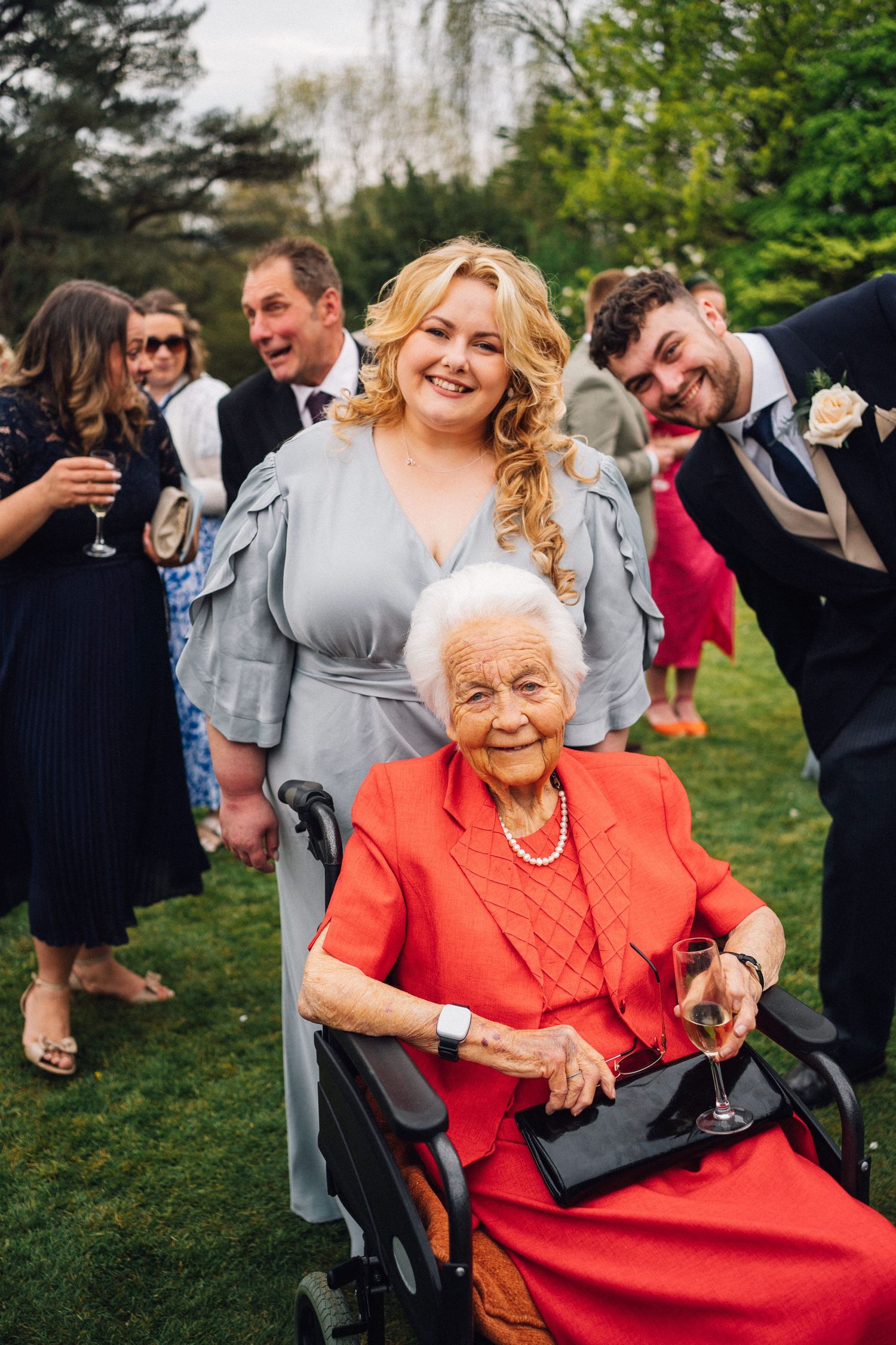 Wedding guest in bright coral dress enjoying festivities outdoors.