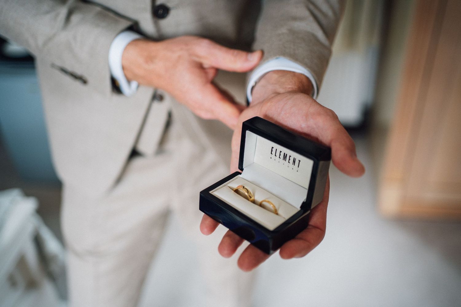 Close-up shots of wedding rings and jewelry details on a wooden surface.