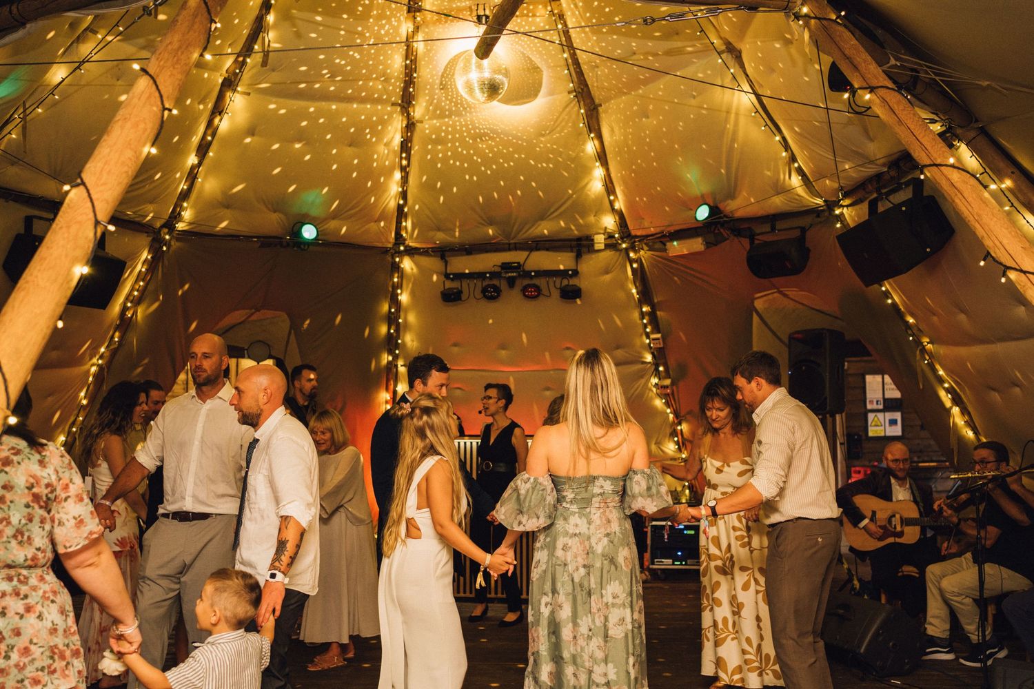 String lights create a warm ambiance inside a tent during an evening celebration.