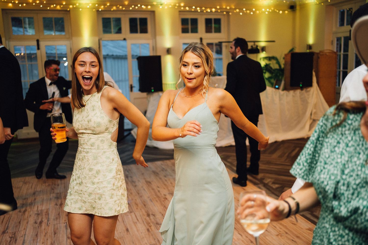 Wedding reception dance party with string lights and wood floors creating festive atmosphere.