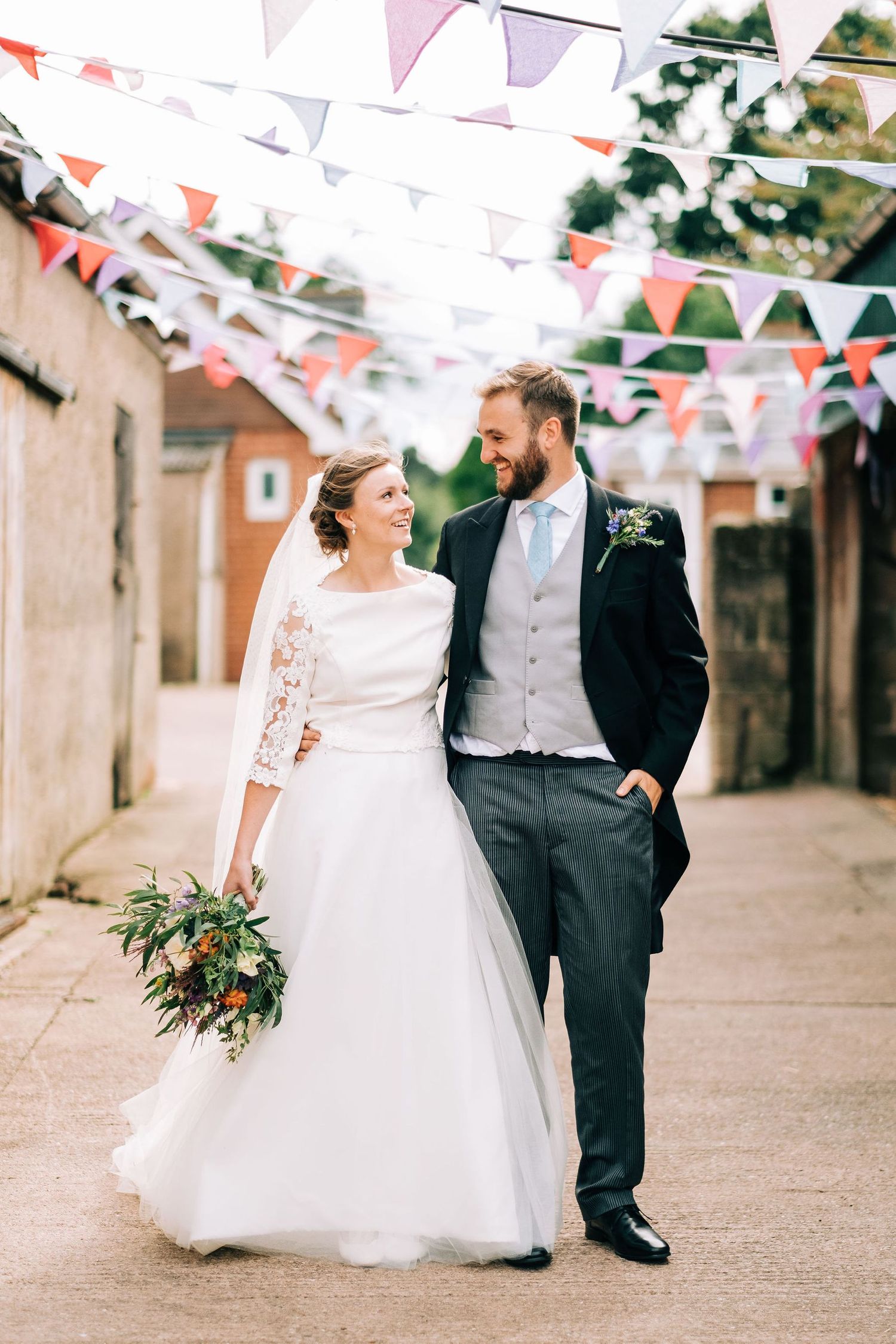 Wedding celebration under festive bunting decorations in a rustic courtyard.