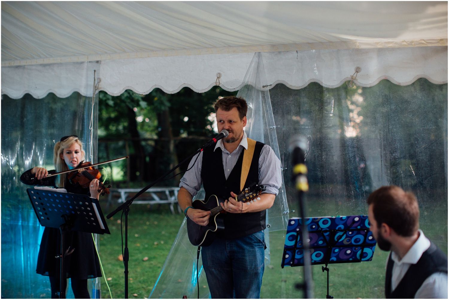 Evening wedding reception with guests mingling under white tent lighting.