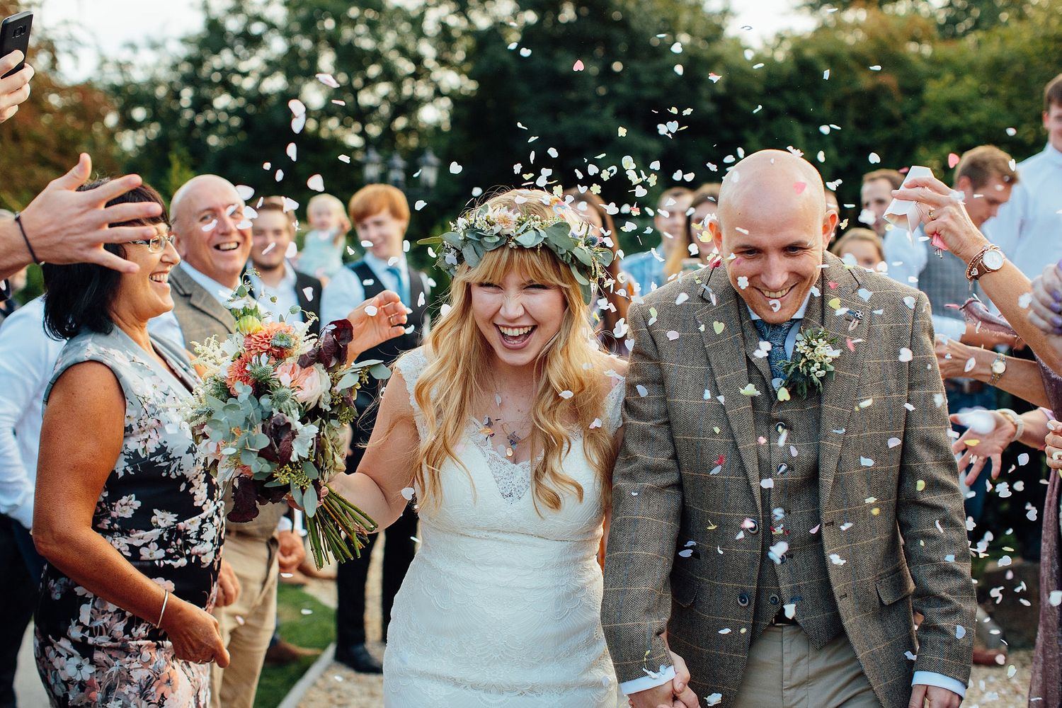 Wedding celebration with confetti being thrown outdoors on a sunny day.