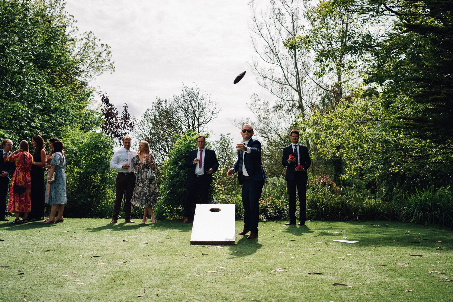 Guests gather on a grassy lawn for an outdoor wedding ceremony.