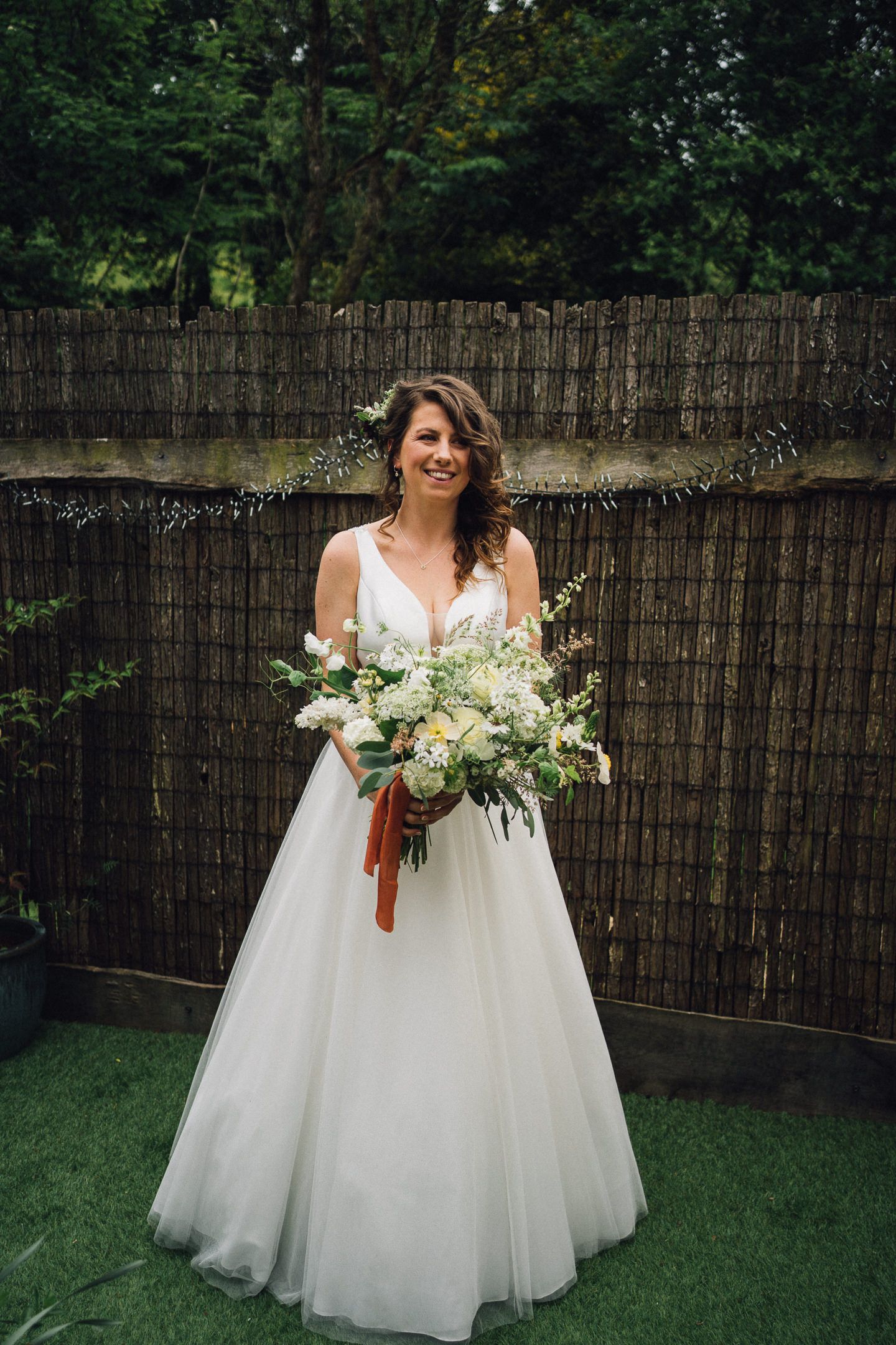 Beautiful white wedding dress and bouquet photographed in a garden setting.