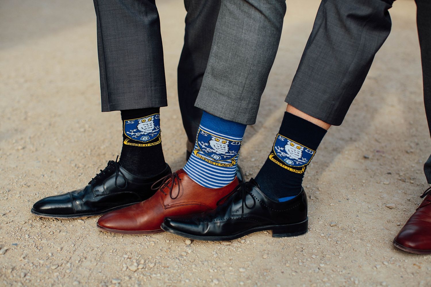 Three pairs of dress shoes with matching patterned blue socks displayed at a wedding.