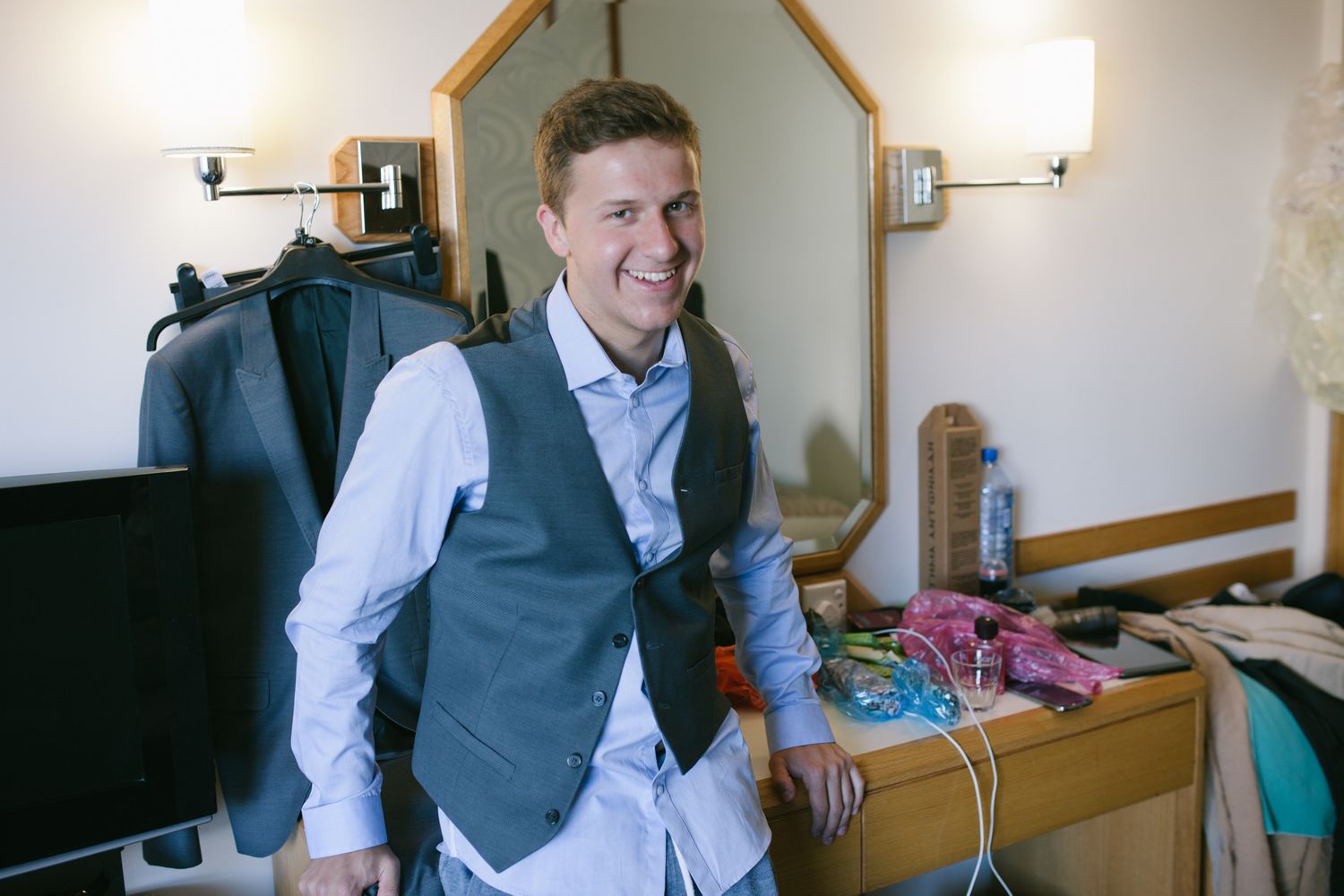 Wedding preparation scene in hotel room with groomsmen getting ready.