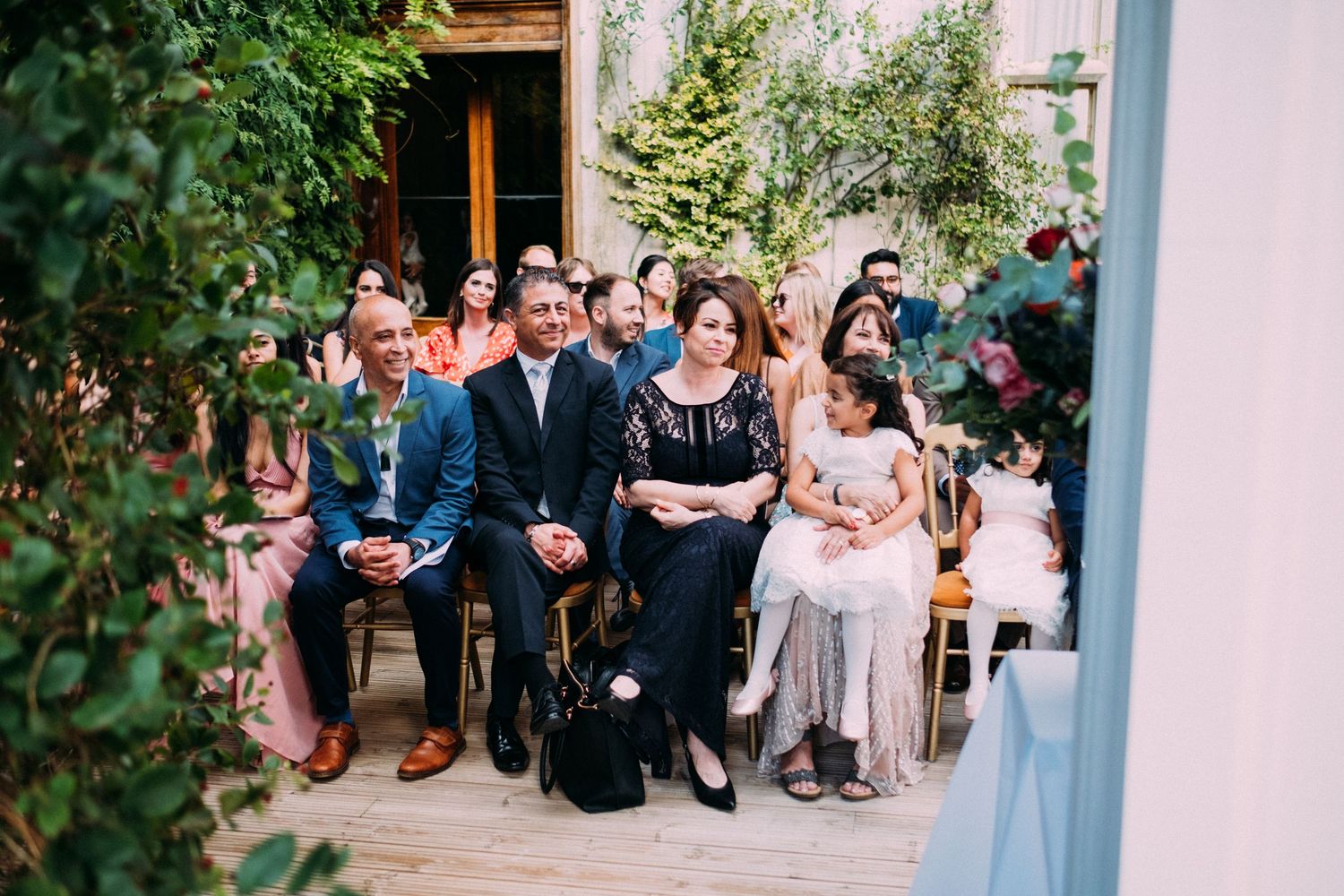 Outdoor wedding venue surrounded by lush greenery and elegant white architecture.