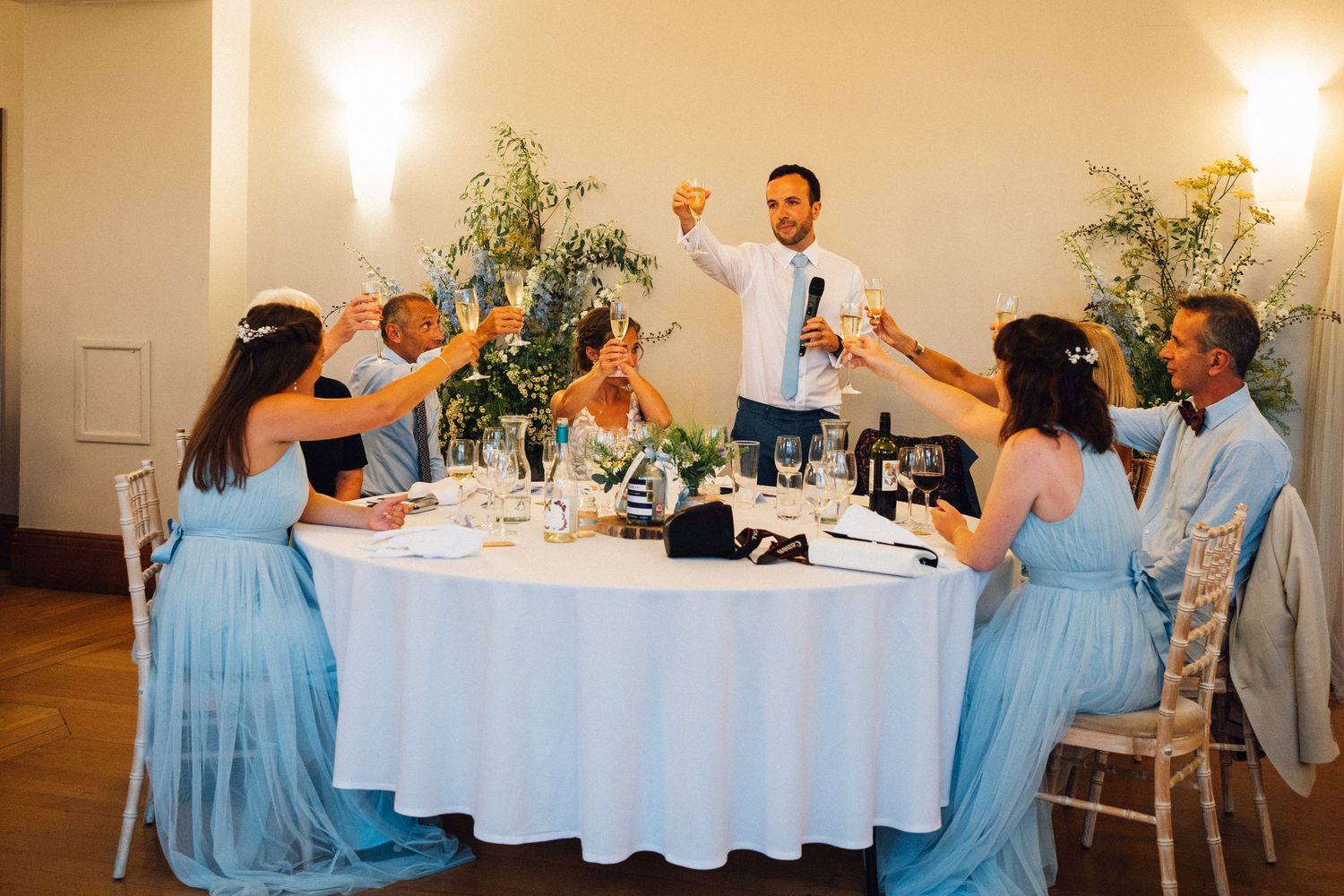 Wedding reception dinner setup with guests seated at round tables decorated in white linens.