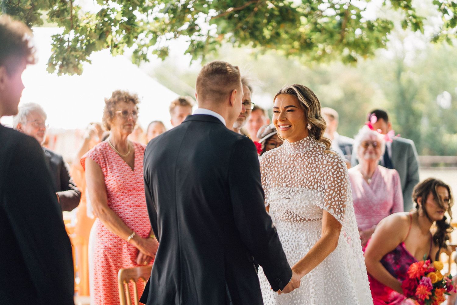 A romantic outdoor wedding reception scene with dancing couples under warm evening light and string lights.