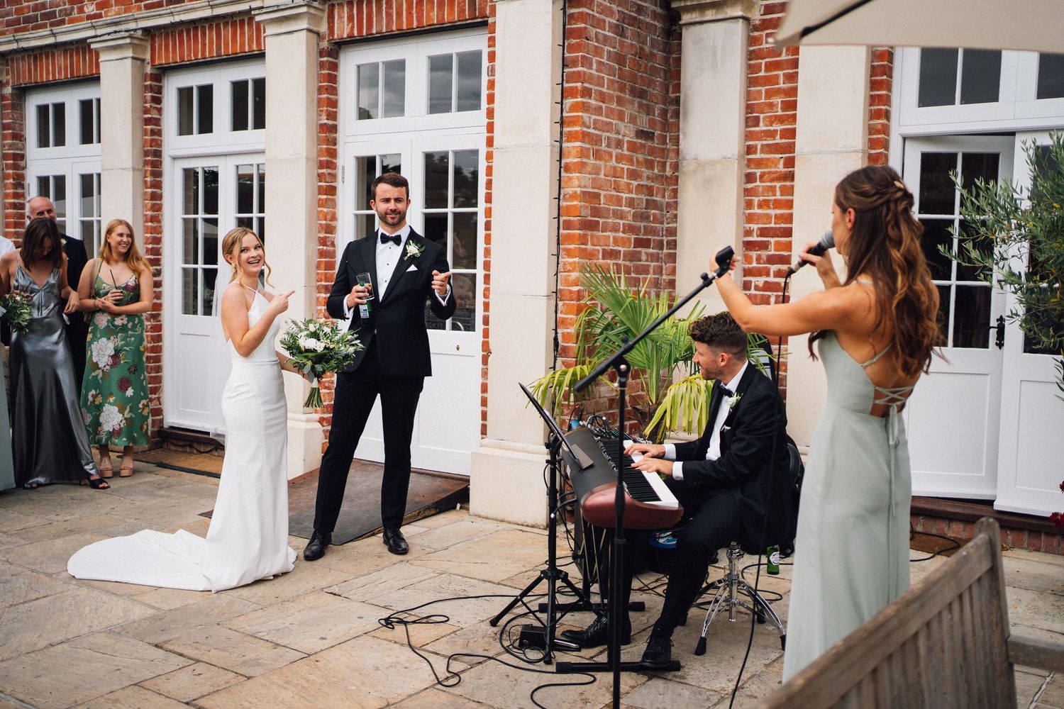 Wedding party poses in front of historic red brick building with white trim and columns.