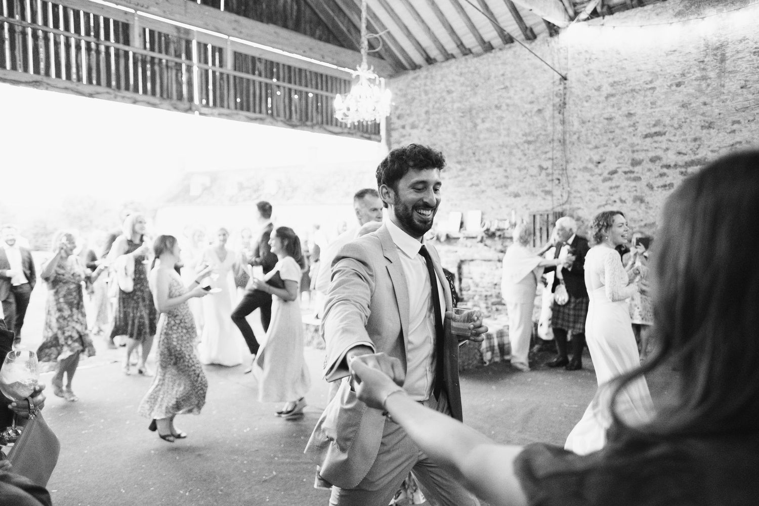 Black and white photo showing wedding celebration inside a converted barn venue.