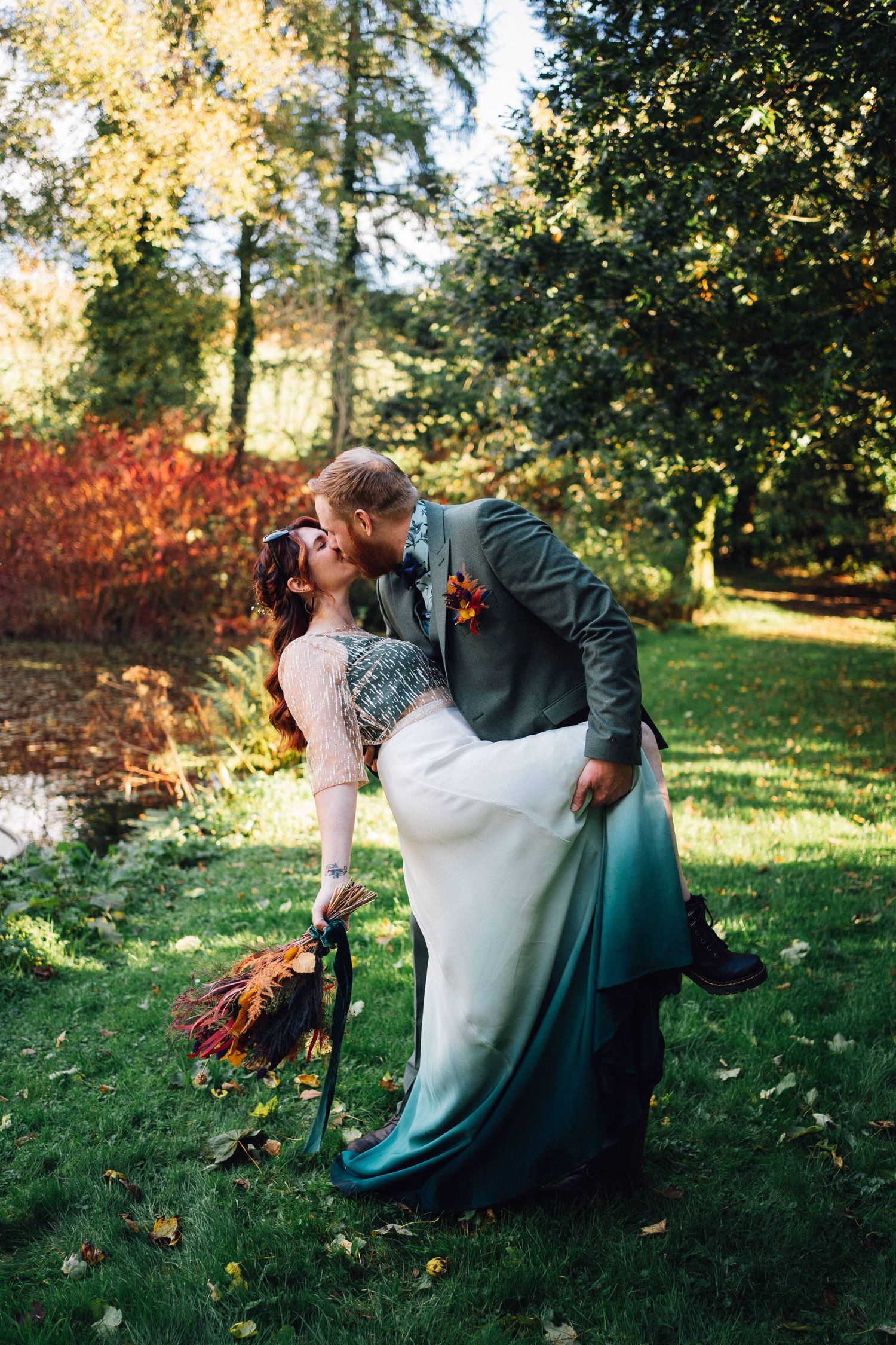 Couple sharing romantic moment on grassy lawn during autumn wedding.