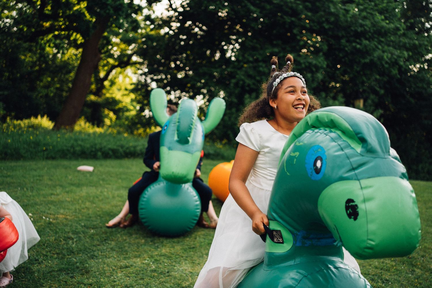 Playful wedding celebration with inflatable dinosaurs on a sunny lawn.