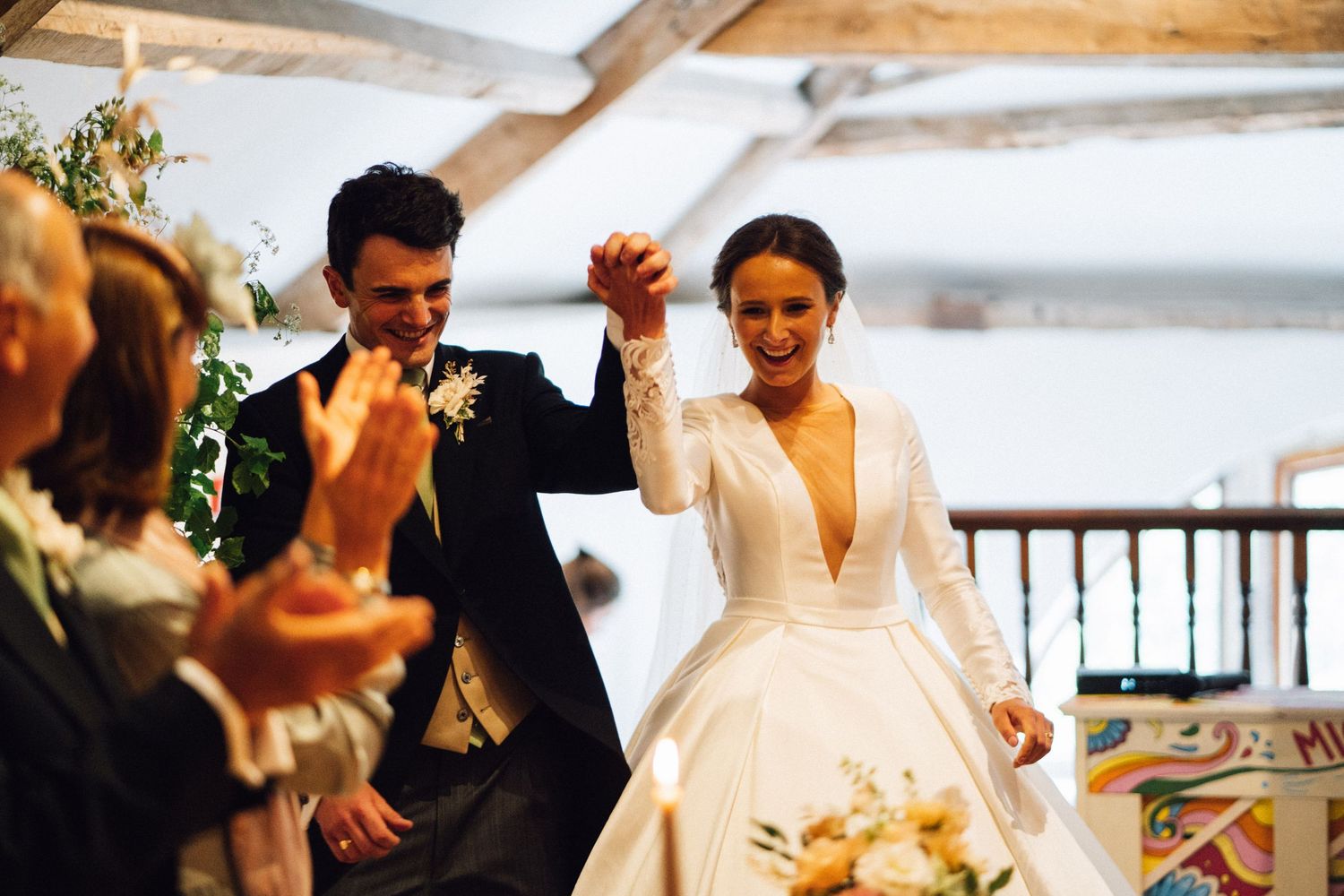 Wedding celebration in progress with guests seated at long wooden tables.