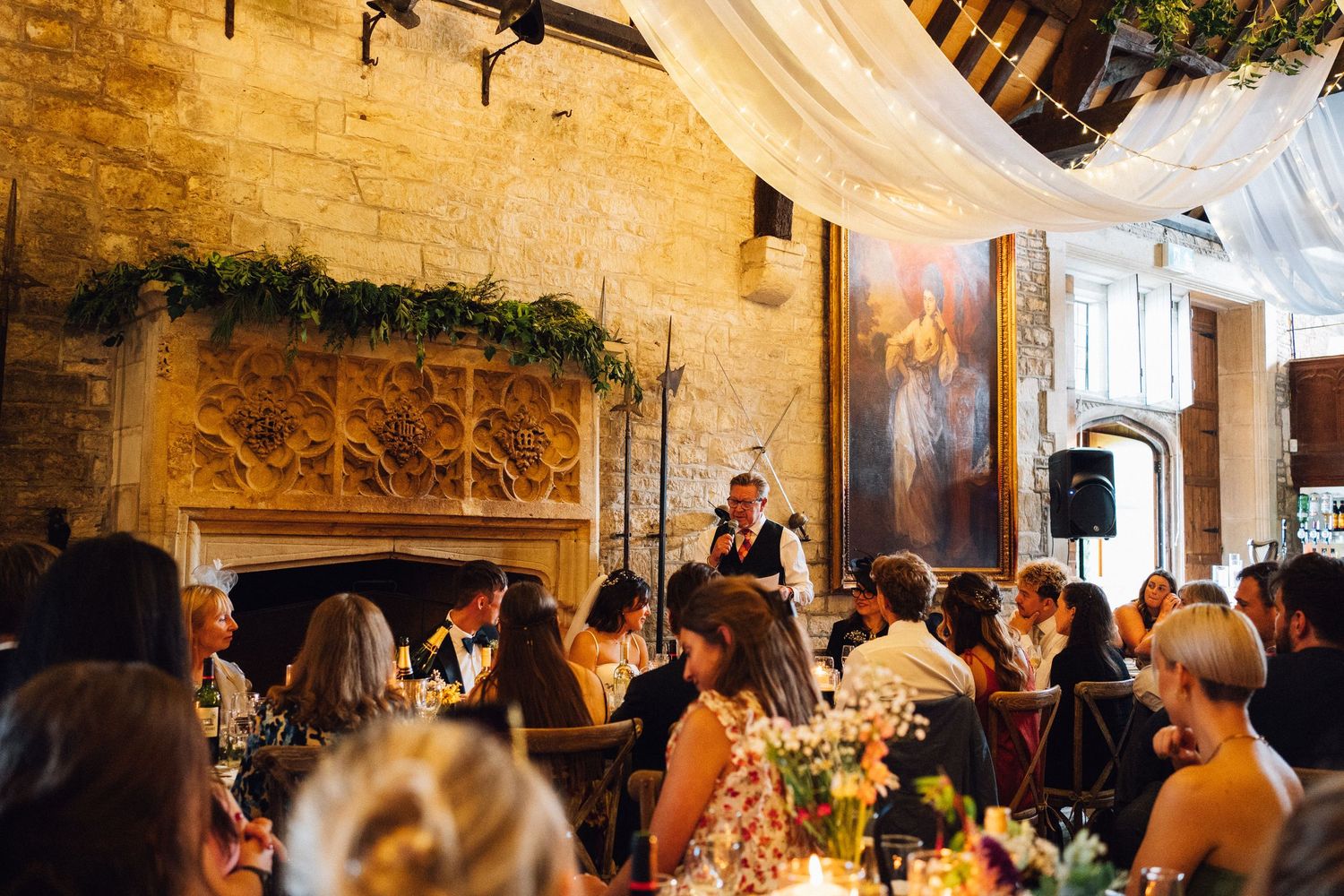 Wedding reception venue with stone walls decorated with greenery and soft lighting.
