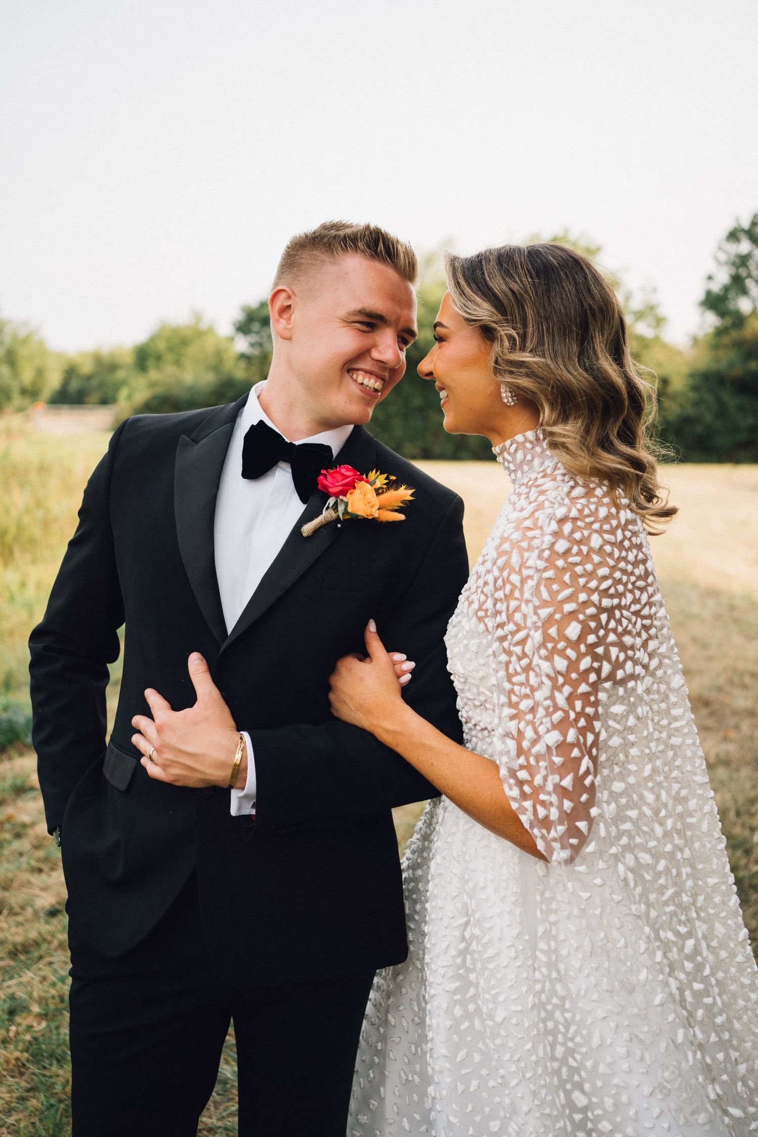 An intimate wedding portrait of a couple sharing a moment in a sunny field.
