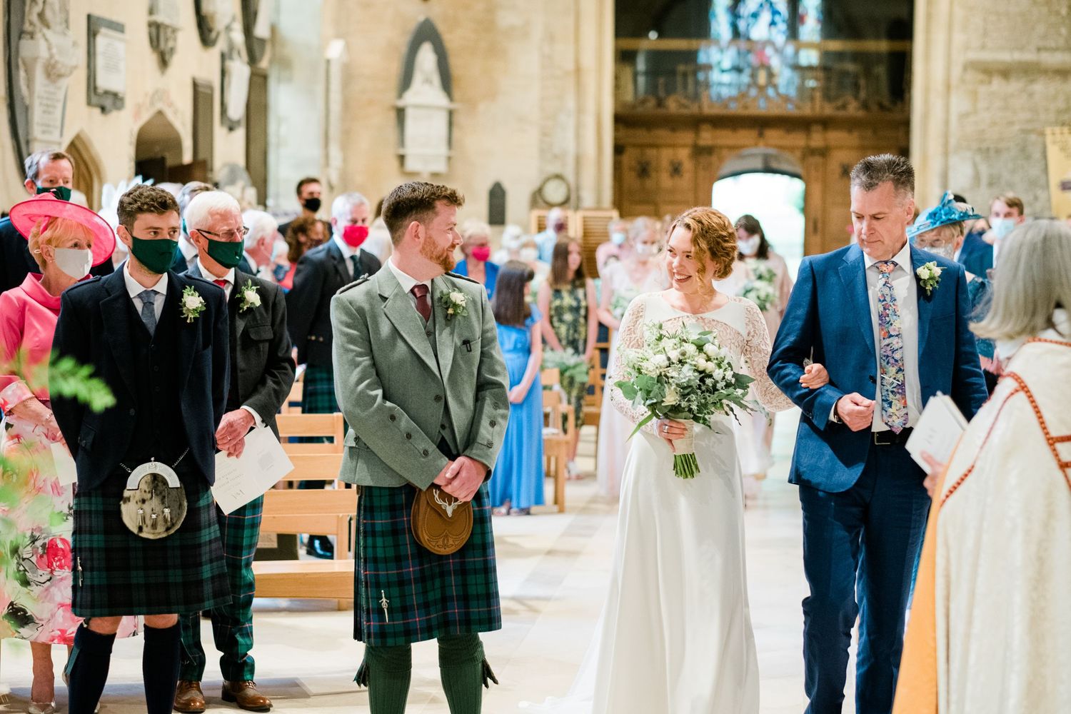 Traditional Scottish wedding ceremony in historic church with guests in kilts and formal wear.