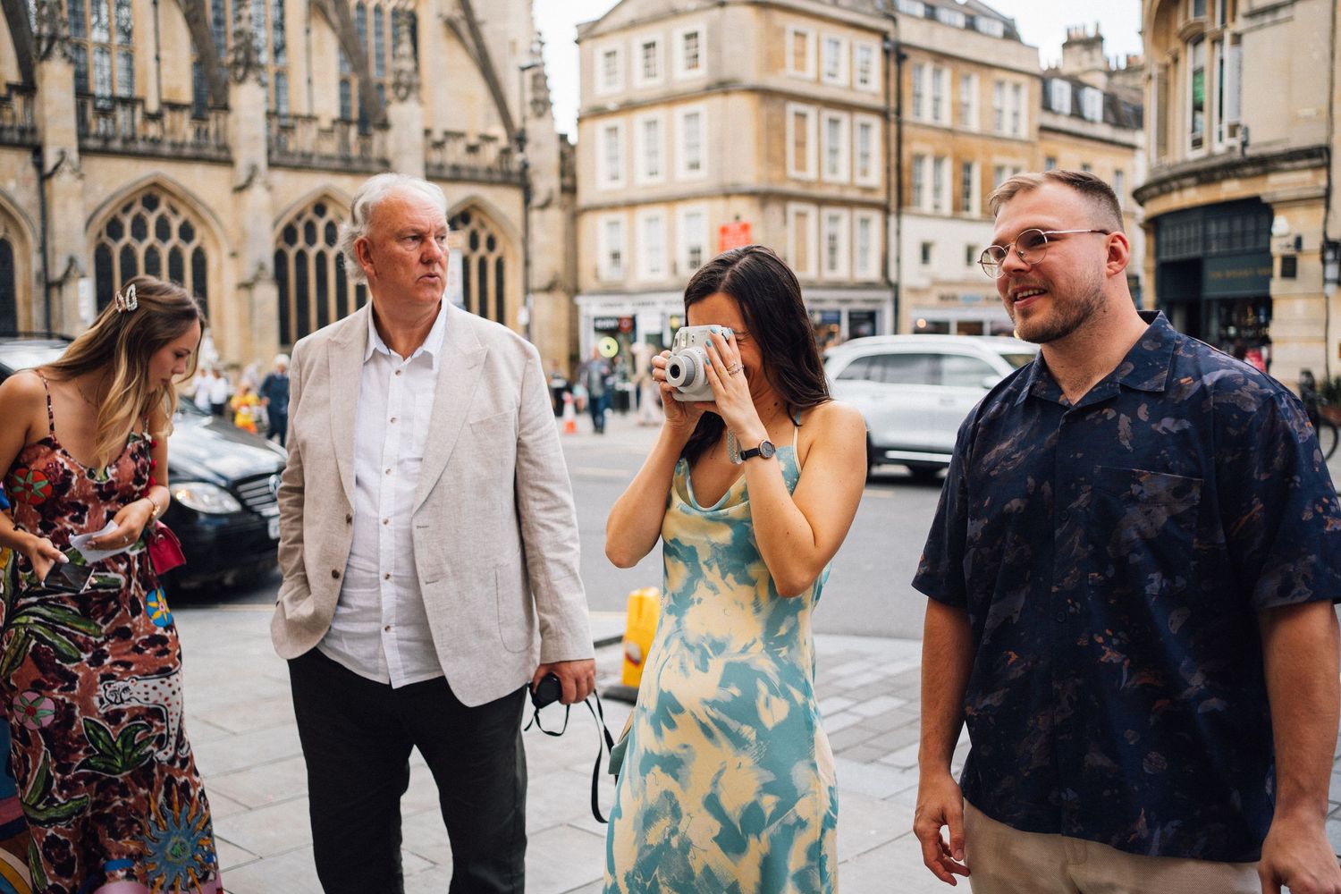 A group of four tourists exploring a historic European city square, with a woman covering her face emotionally.