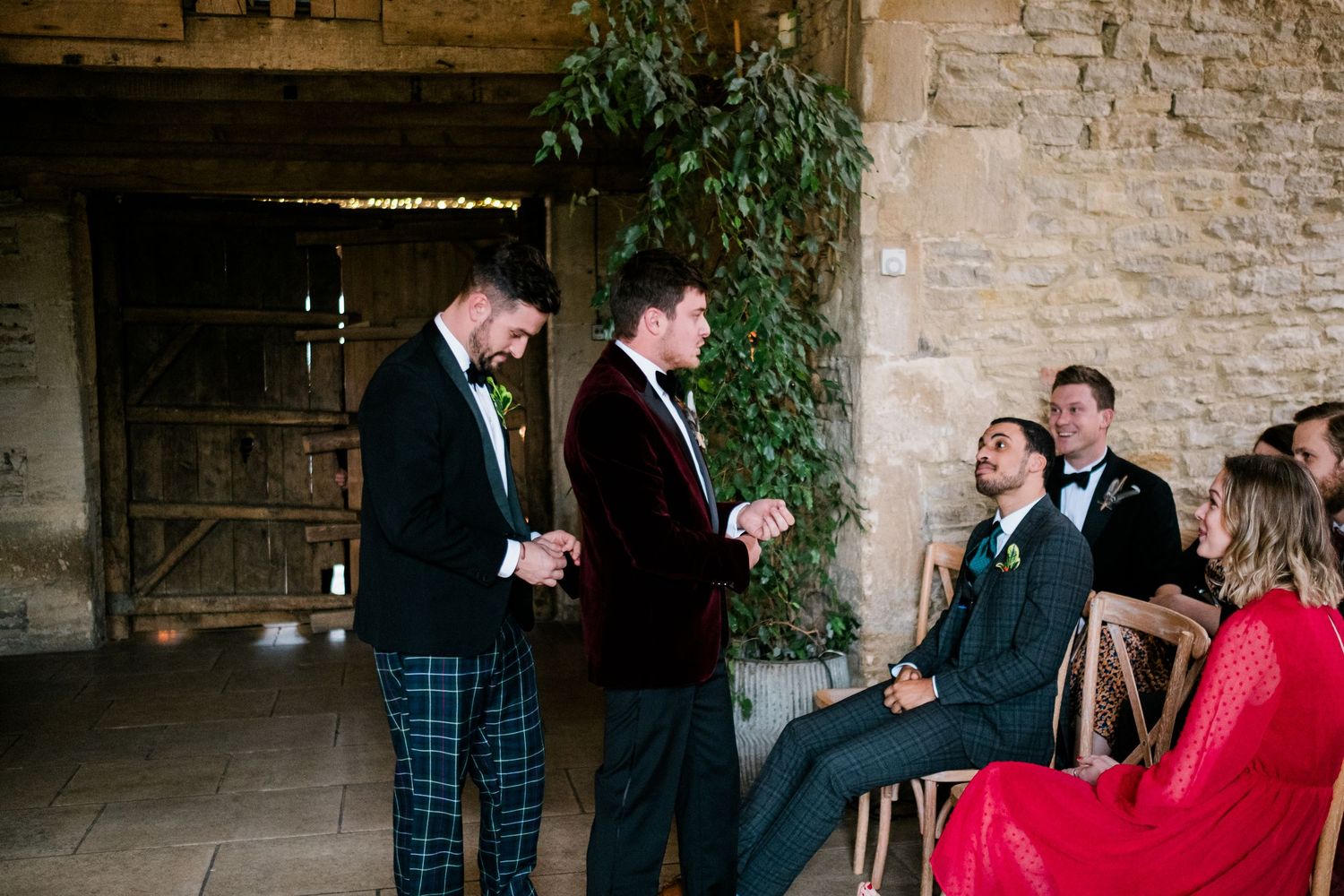 Wedding guests share joyful reactions during a ceremony in a rustic stone venue.