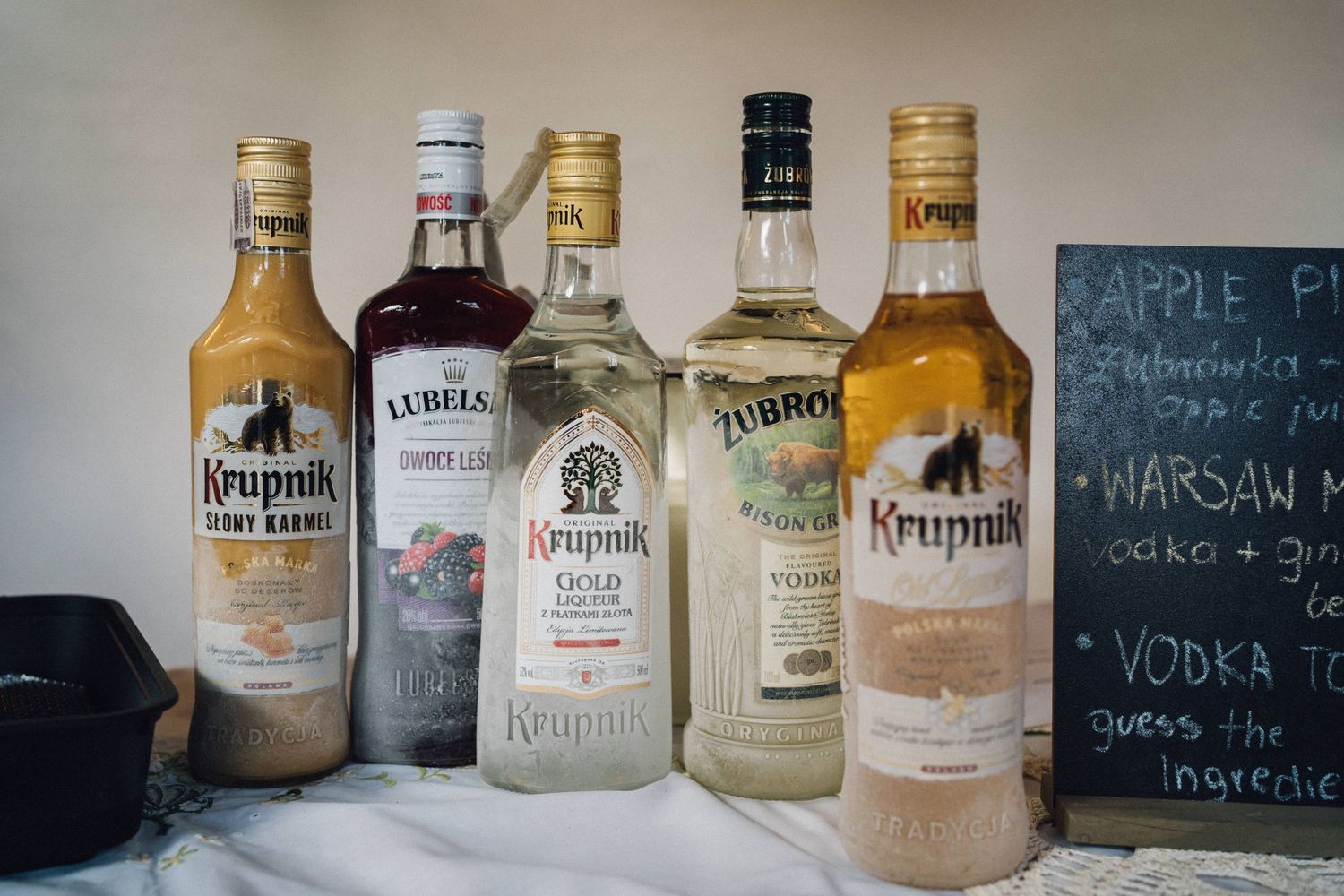 Various vodka and liquor bottles displayed at wedding bar with chalkboard menu.
