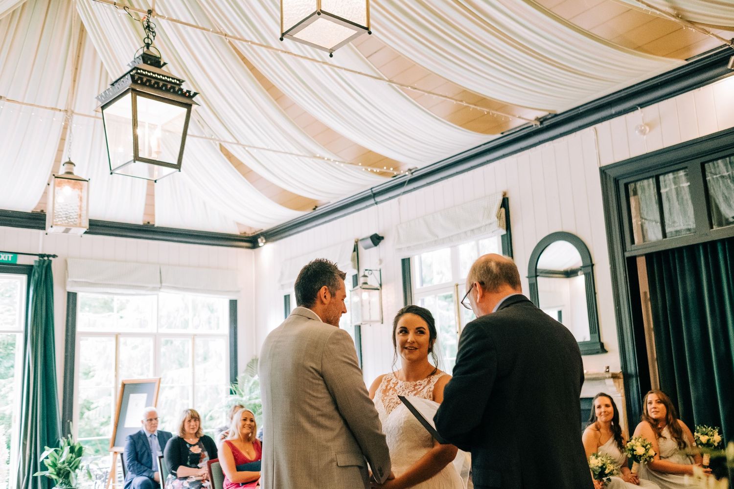 Wedding reception space decorated with draped fabric ceiling and elegant lighting fixtures.