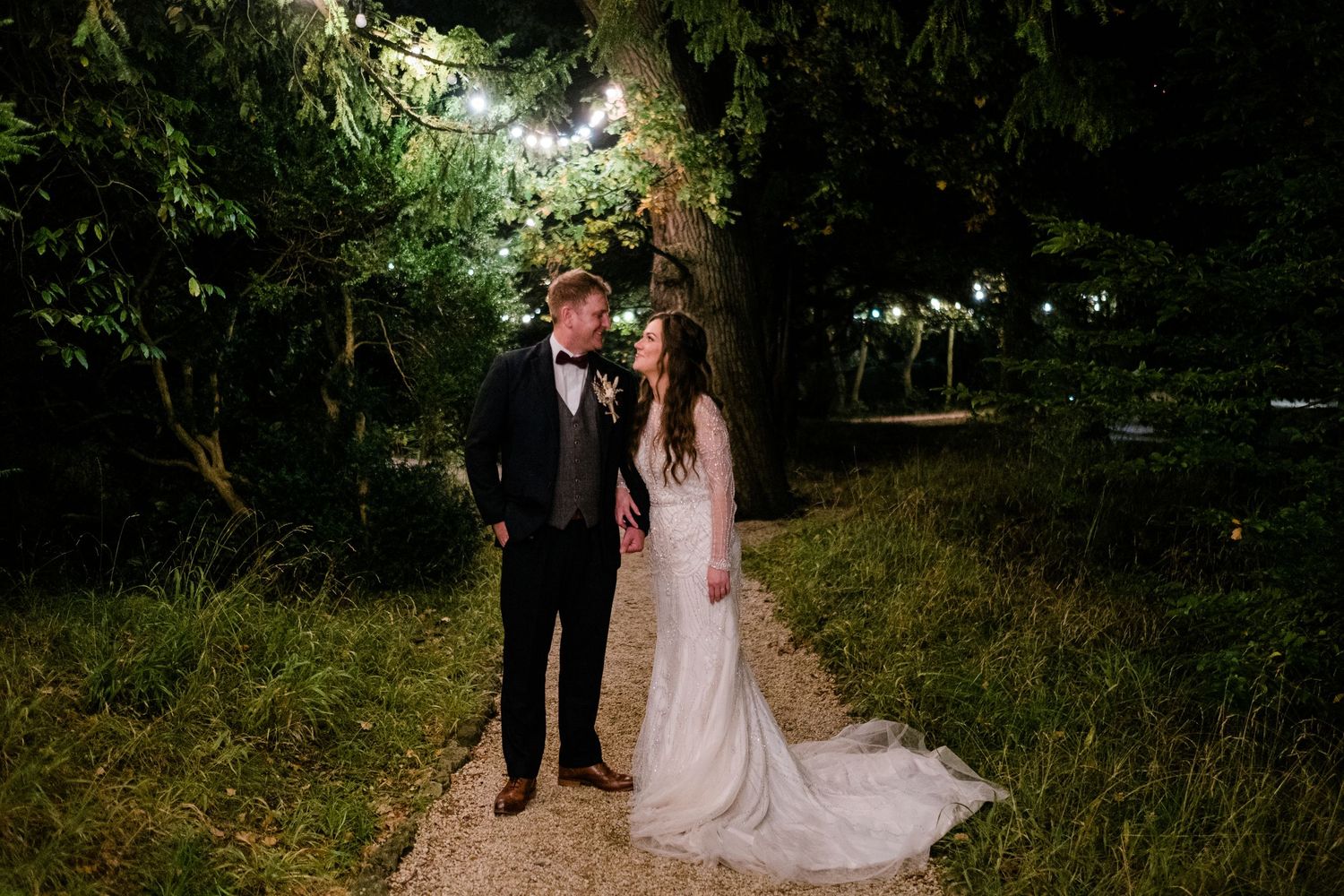 Evening wedding photos taken on scenic garden path with ambient lighting.