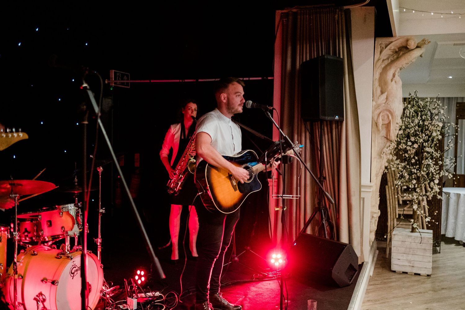 Live band performing at a wedding reception with dramatic red lighting and instruments.
