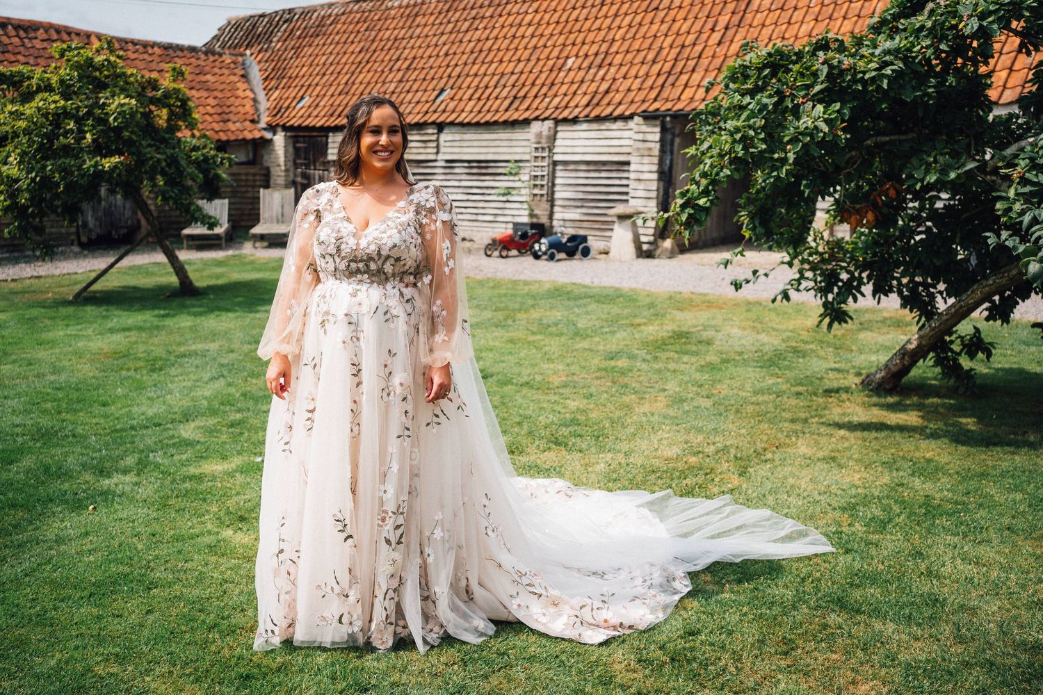 A wedding couple shares a joyful moment in front of a rustic brick building with terracotta roof tiles.